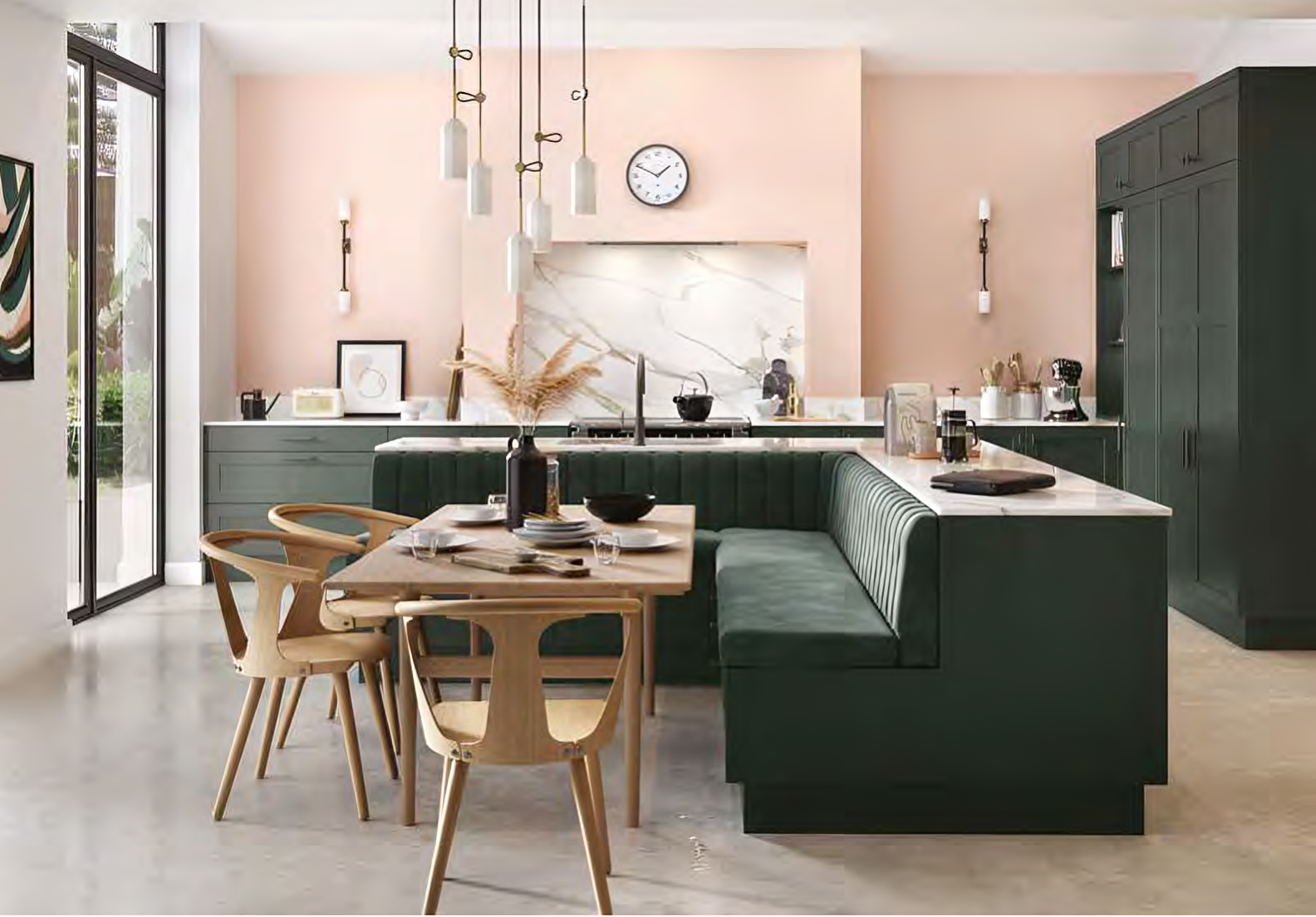 Modern kitchen with green cabinetry, marble backsplash, U-shaped seating with velvet cushions, wooden dining table, and chairs under hanging pendant lights.