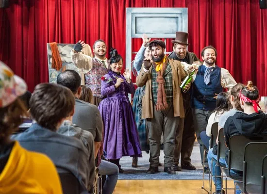 6 performers in costume in front of an audience of students
