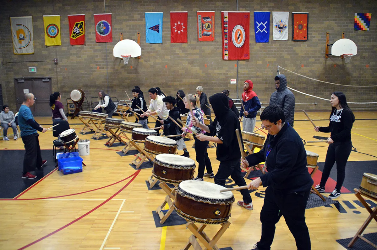 High school aged students in a school gym learning to play Taiko drums
