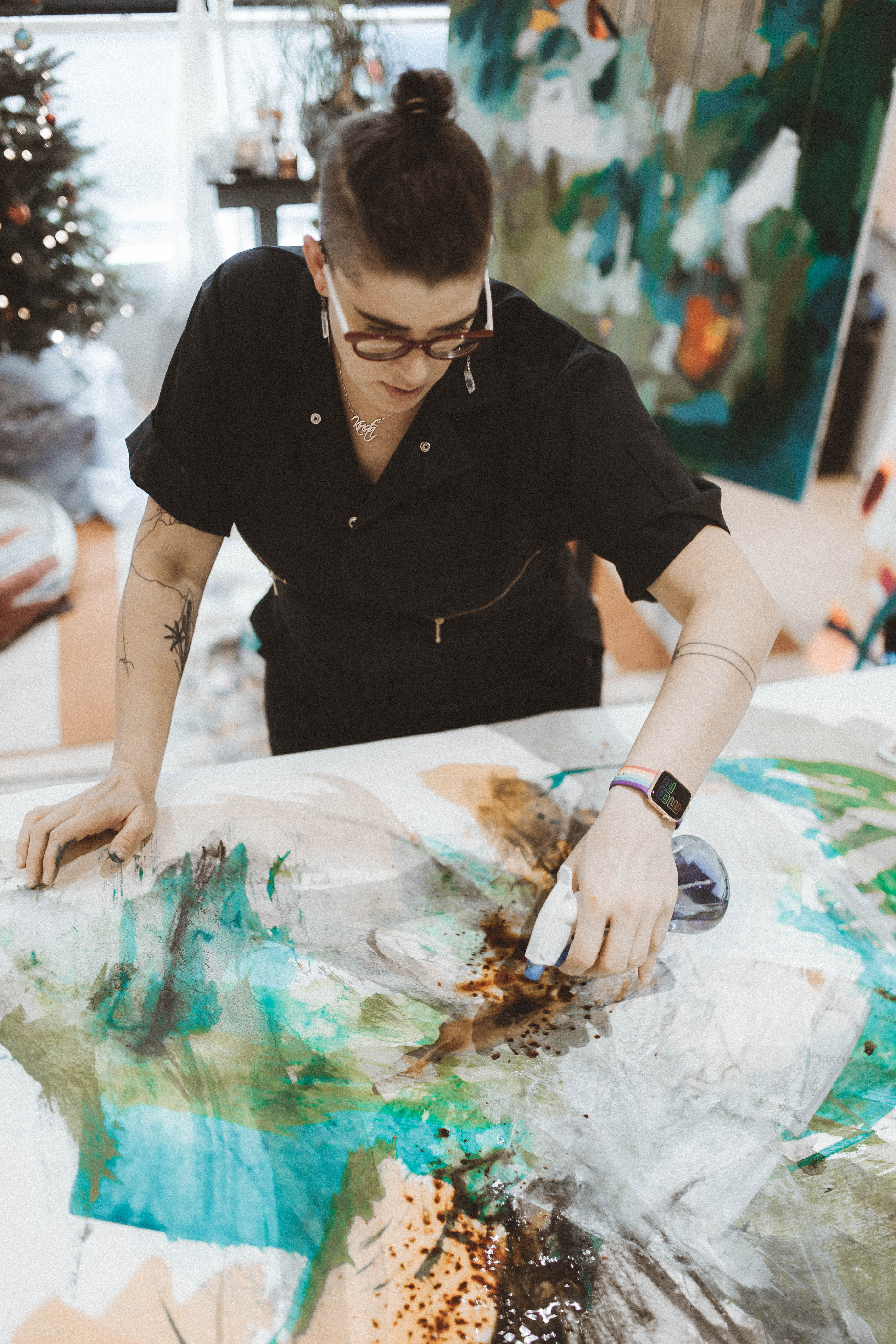 Solo artist wearing a black jumper working on a screen print in turquoise and brown