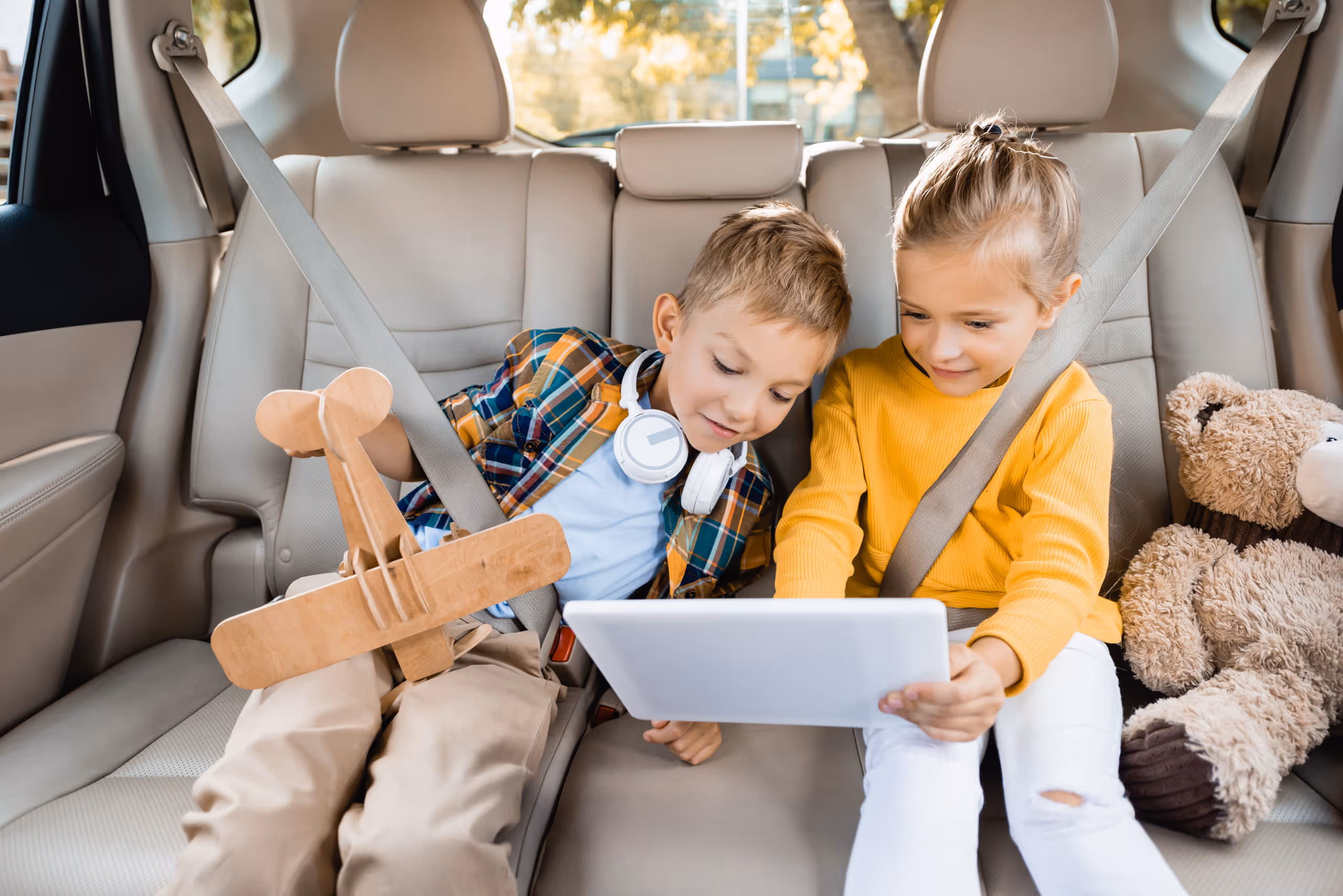 Young kids in back seat sharing a mobile device screen 