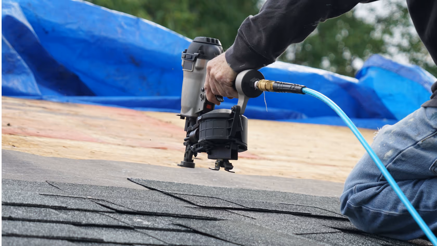 A roof installer using a nail-gun to repair the roof after a storm