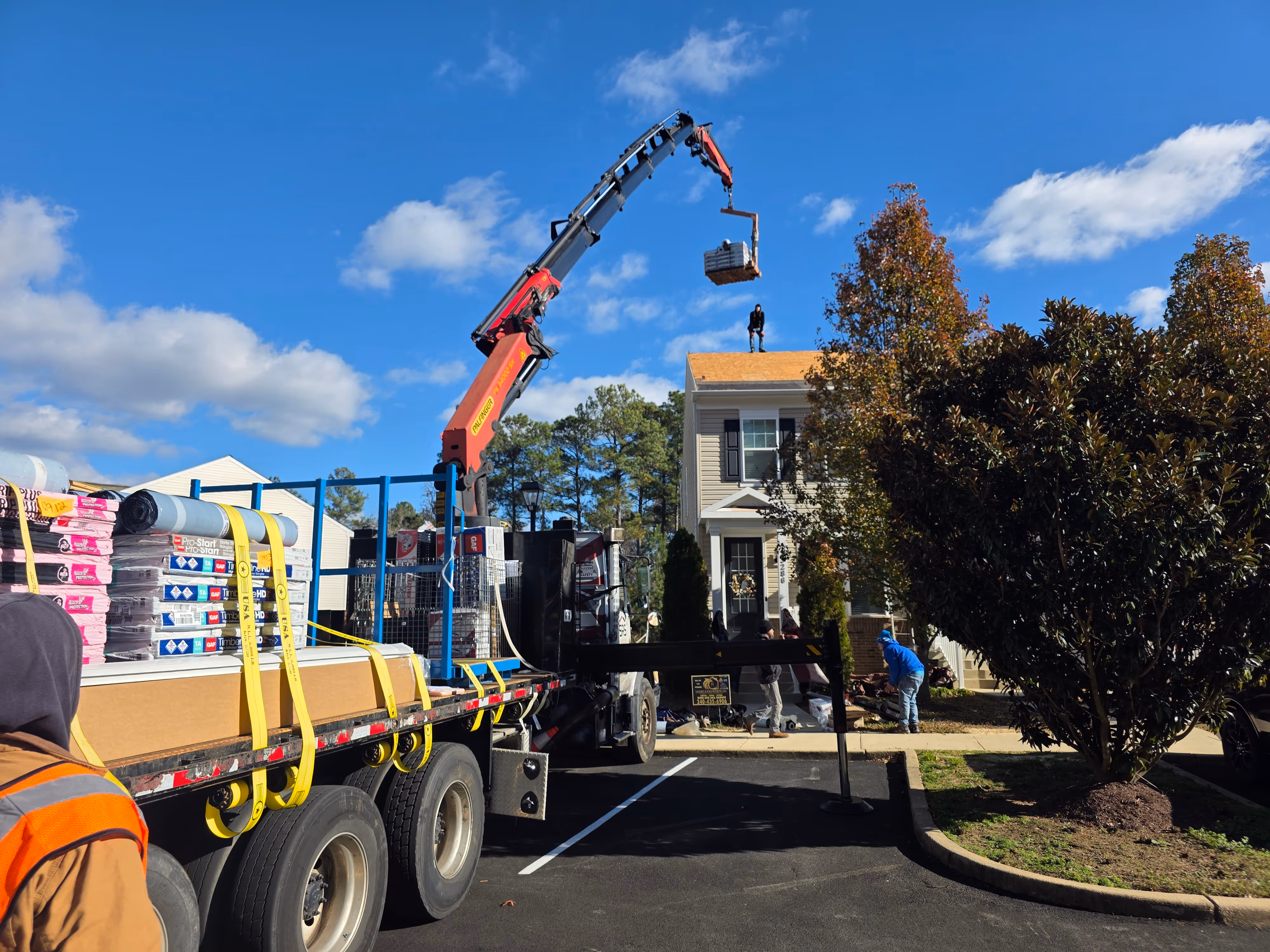 A photo of a crane loading a townhome with Atlas Pinnacle Pristine roof shingles for a insurance-paid roof replacement in North Beach, Maryland by Golden Eagle Roofing, LLC