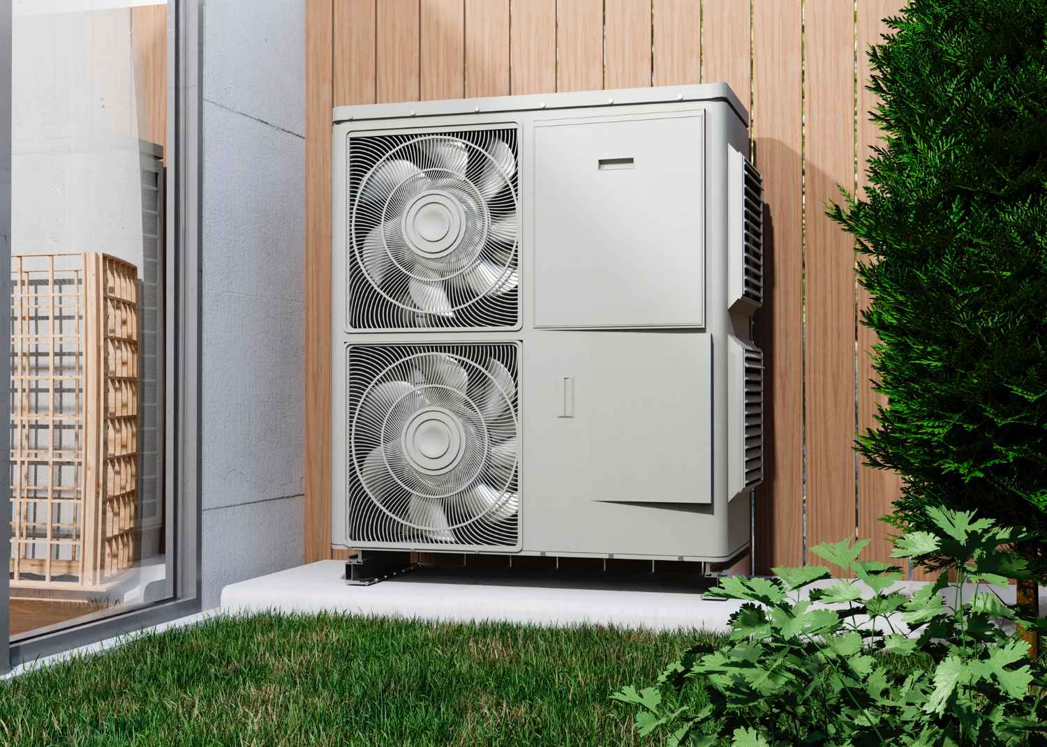 Outdoor air conditioning unit with two large fans mounted on a raised platform against a wooden fence, surrounded by green grass and shrubs.