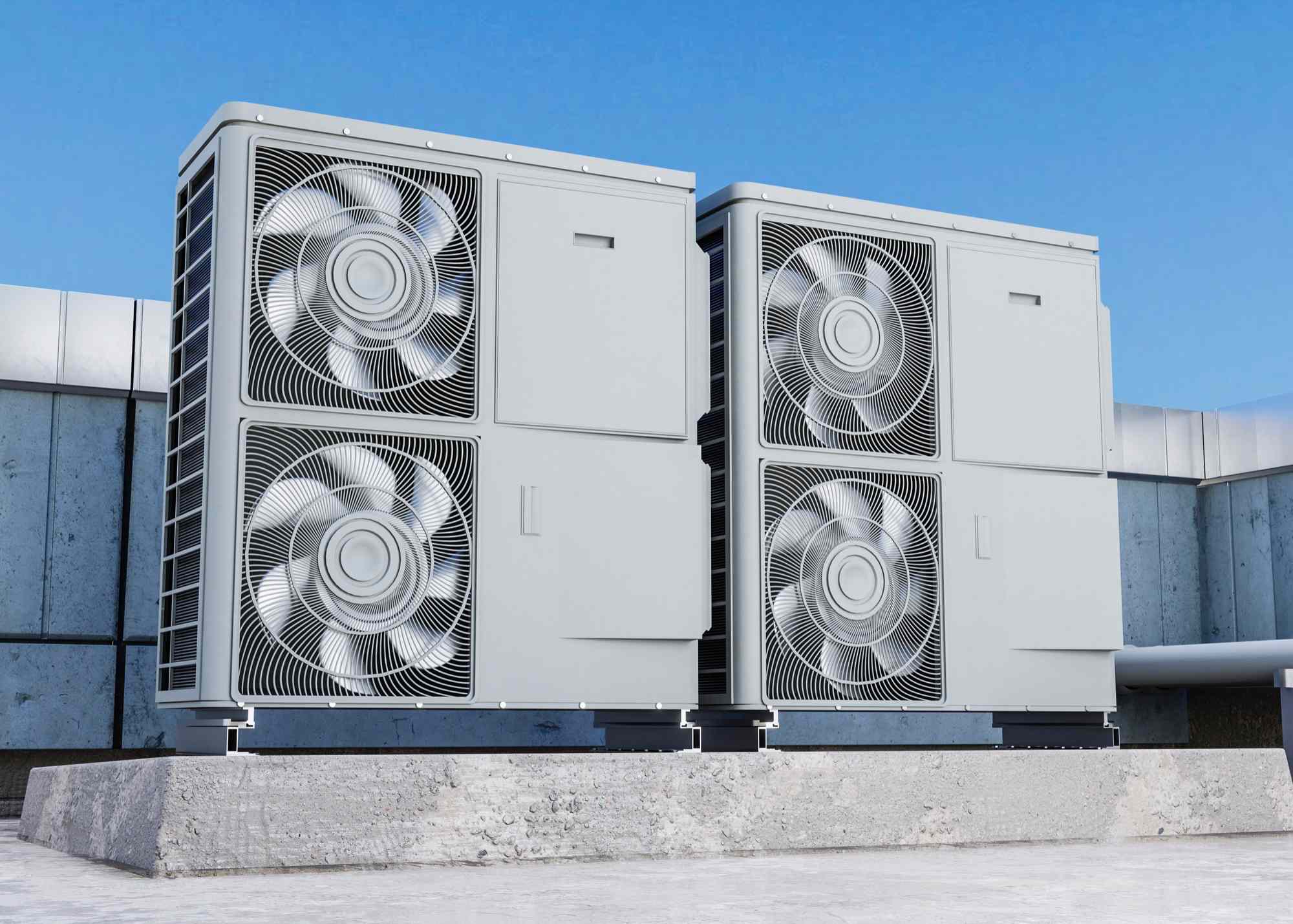 Two large industrial HVAC units with fans on a rooftop under a clear blue sky.