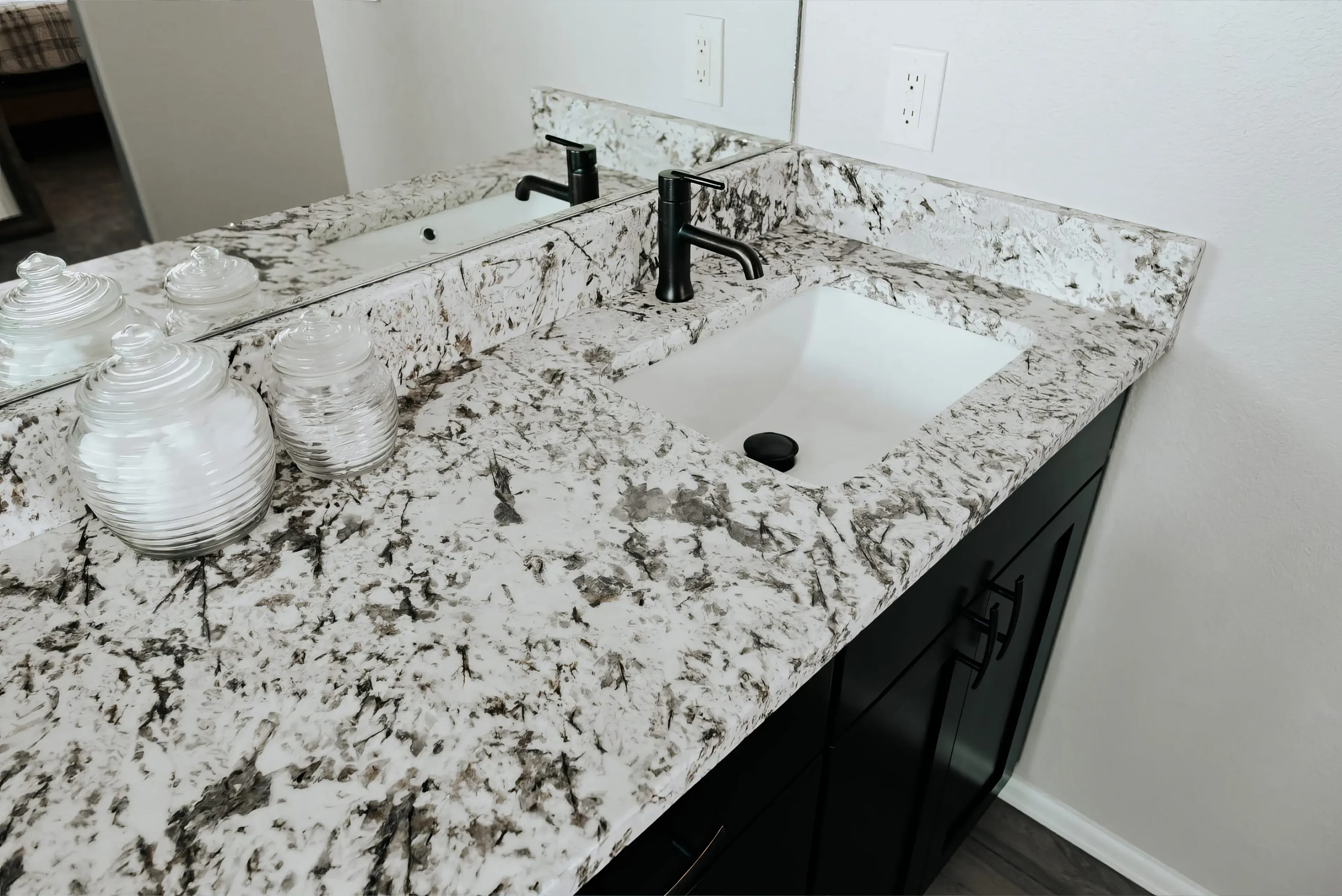 A close up photograph of a bathroom vanity with white granite countertops.