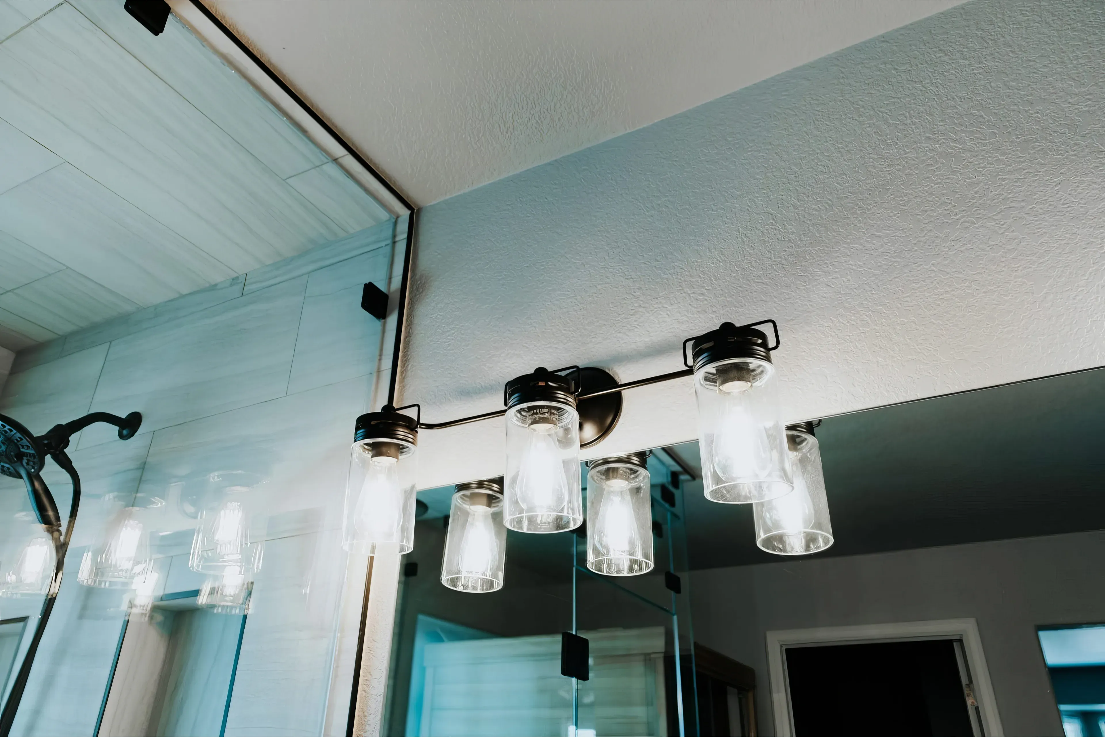A close-up photograph of a modern light fixture in a newly remodeled bathroom.