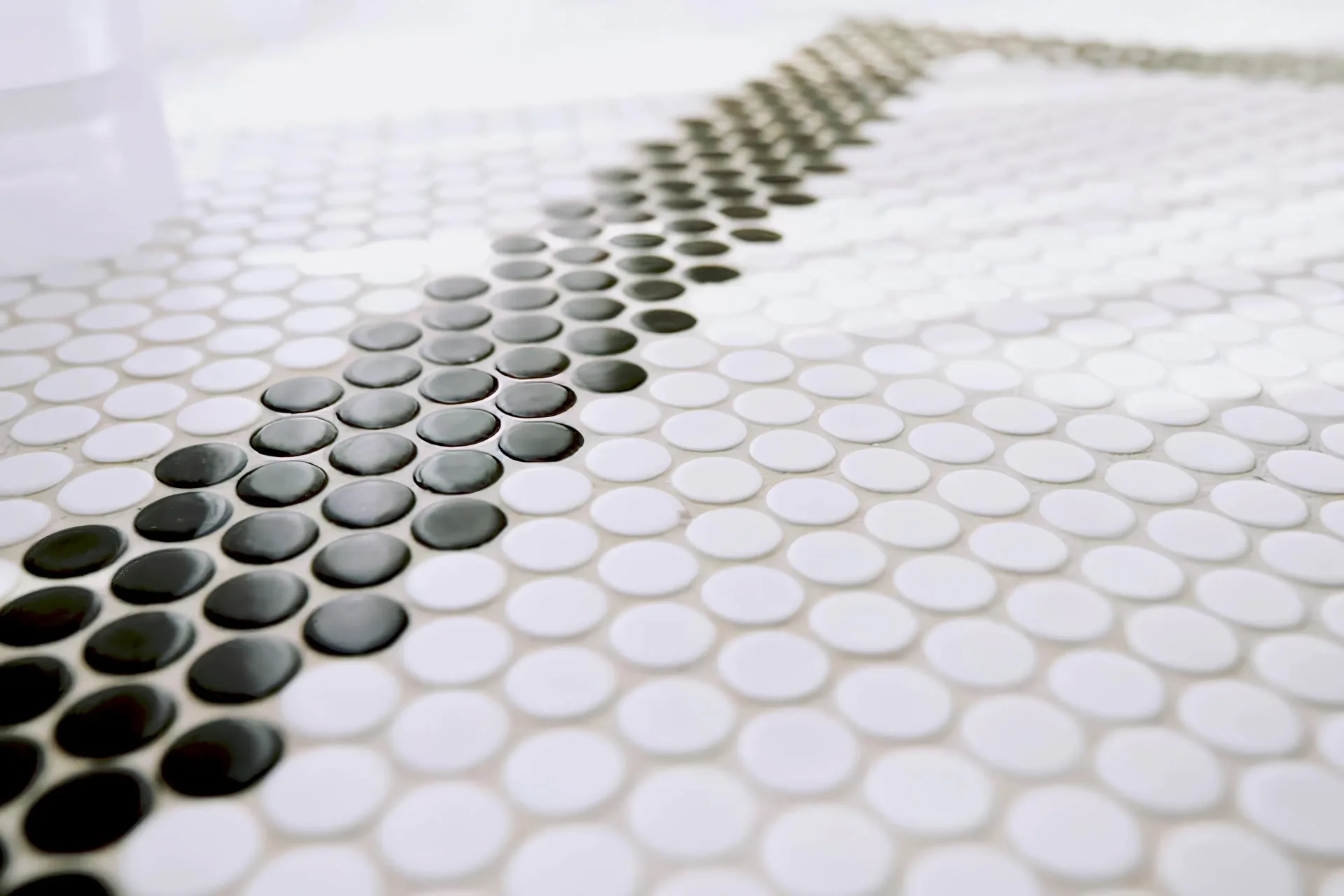 A close up photograph of round white and black penny tile with a custom design.