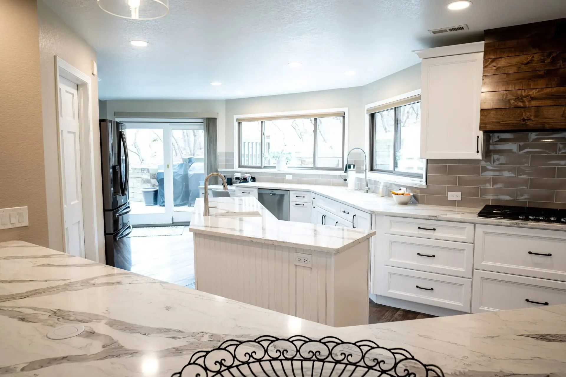 Spacious kitchen with white cabinets, marble countertops, and stainless steel appliances. Large windows and sliding glass door provide natural light.