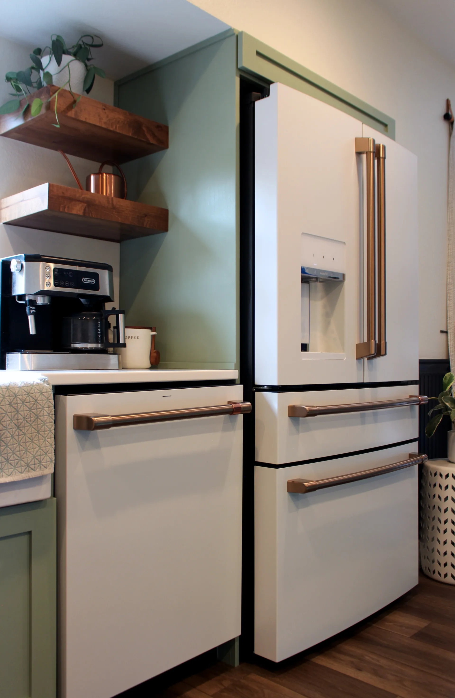 A photograph of a matching white café dishwasher and french door fridge with champagne gold handles.