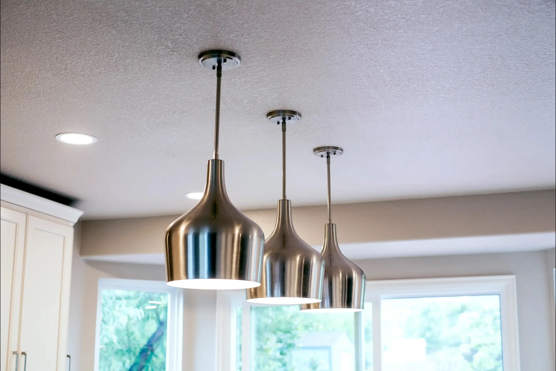 A close-up photograph of stainless steel pendant lights over the kitchen island.
