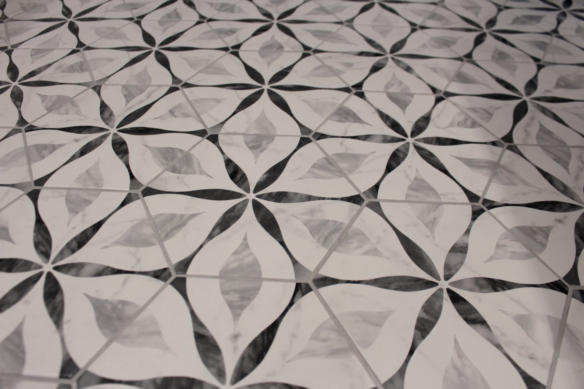 Intricate black and white tile floor with a geometric floral pattern. The symmetrical design creates a sleek, modern, and stylish ambiance.