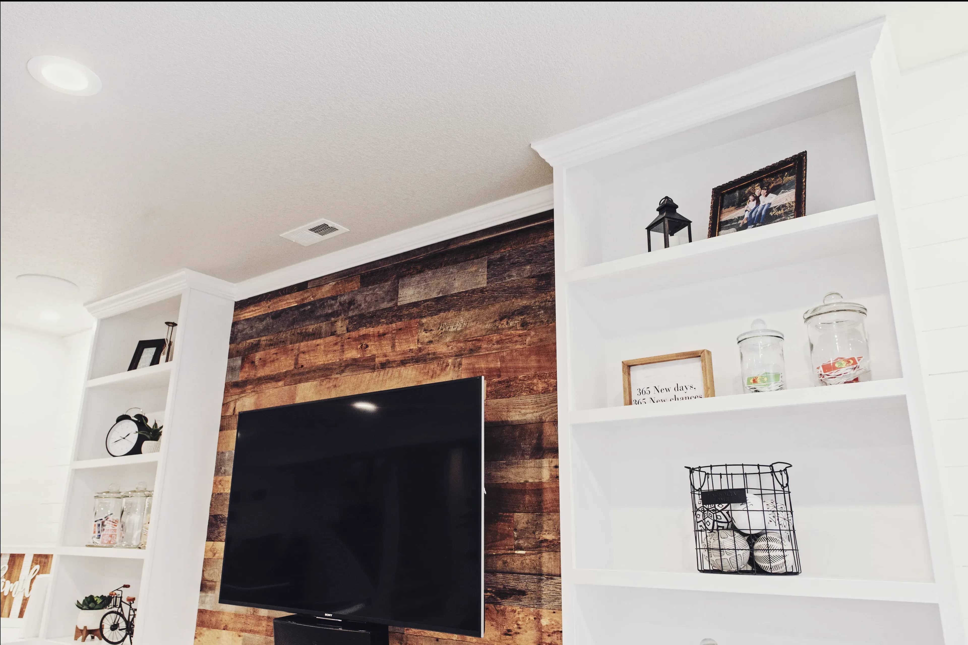 Newly installed built in custom white shelving and cabinets to a basement remodel wall