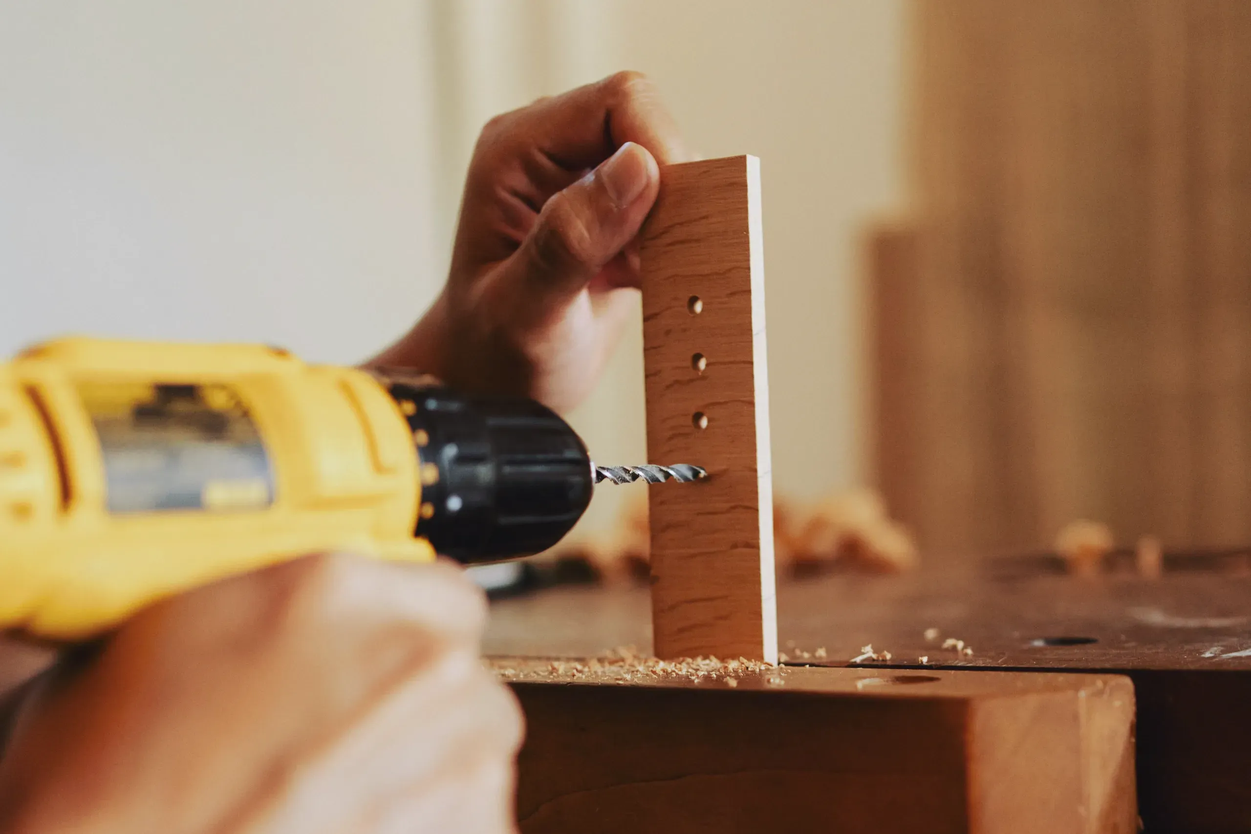 A pair of hands drilling into a piece of wood for a handyman project.
