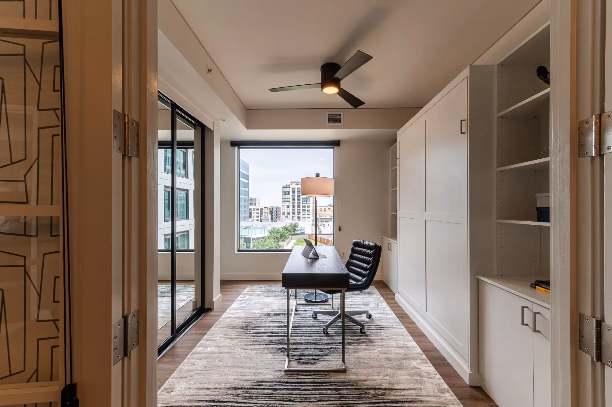 Closet Factory custom walk-through closet with concealed storage and black-framed mirrored doors in den.