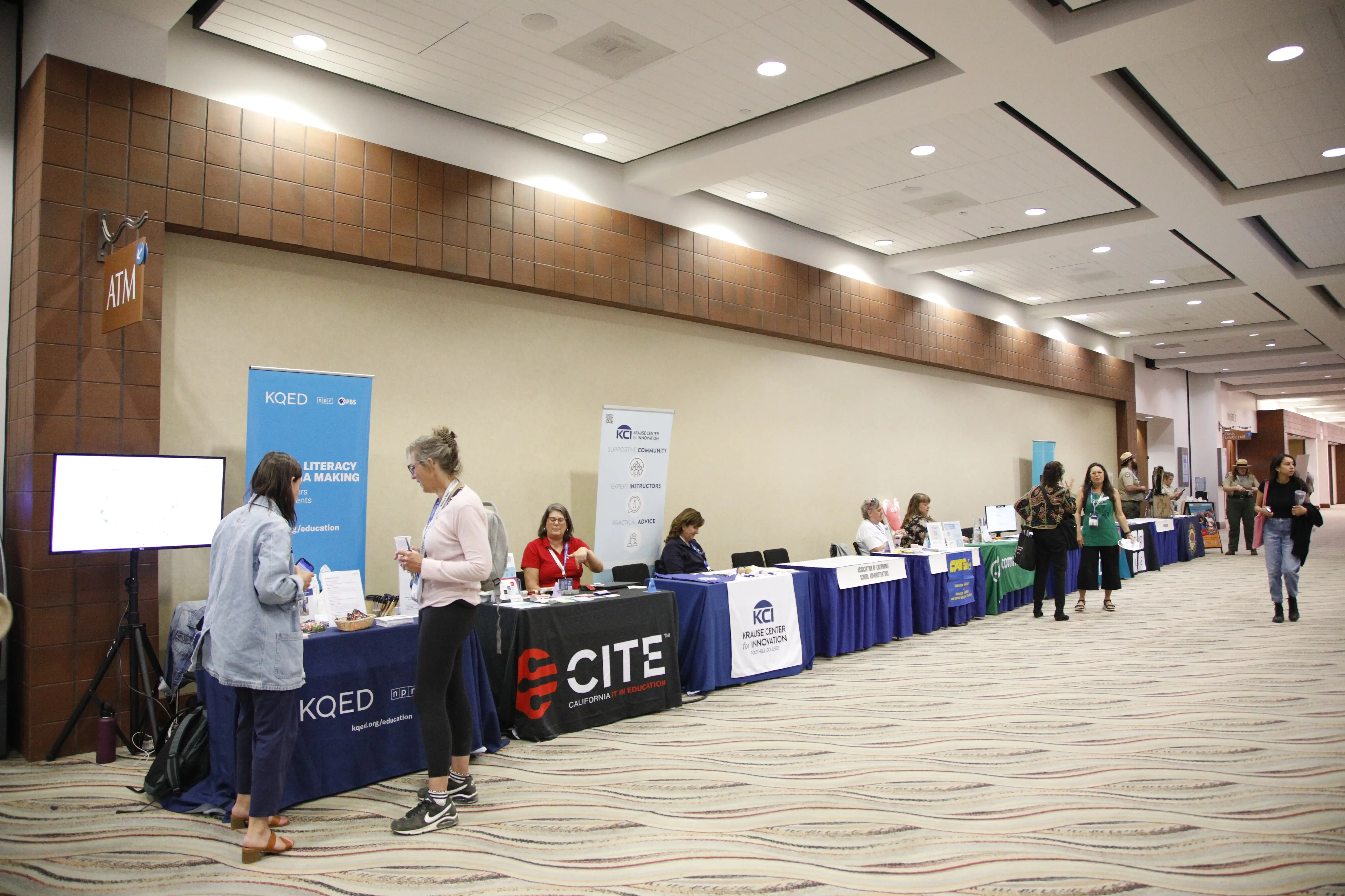 K-12 education conference expo hall with EdTech vendor booths and attendees browsing displays