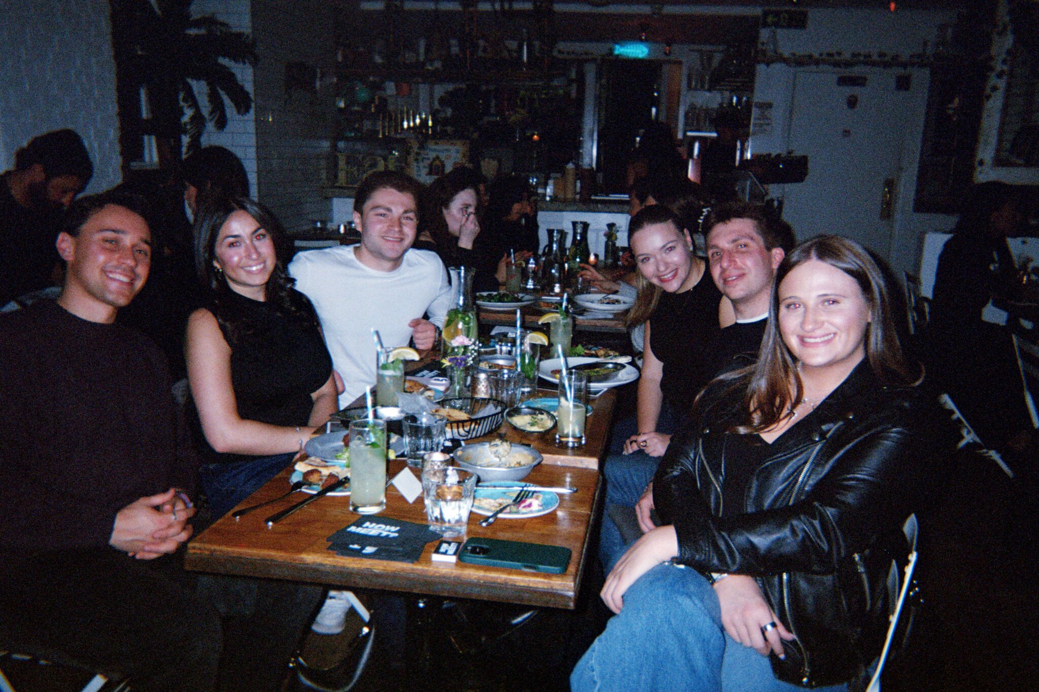 A long How Jew Meet dinner table full of guests