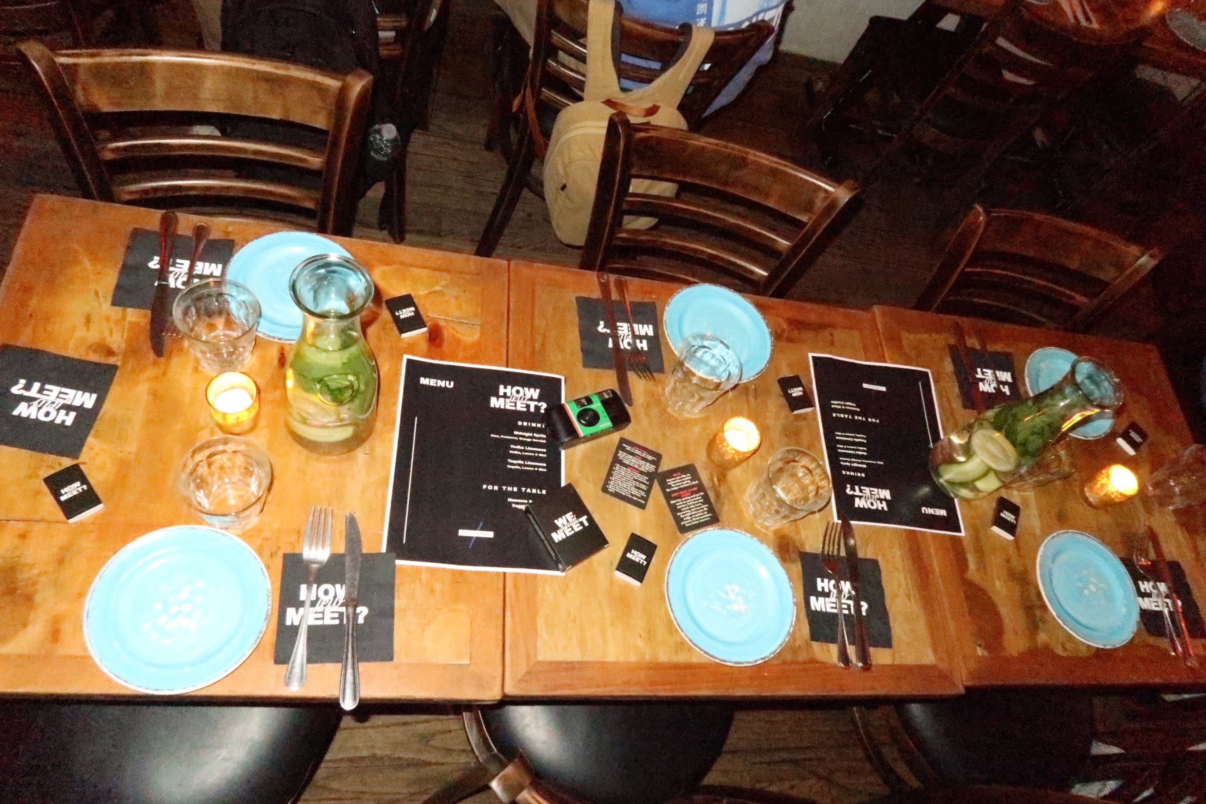 A long How Jew Meet dinner table set with menus, We Should Meet cards, and candles