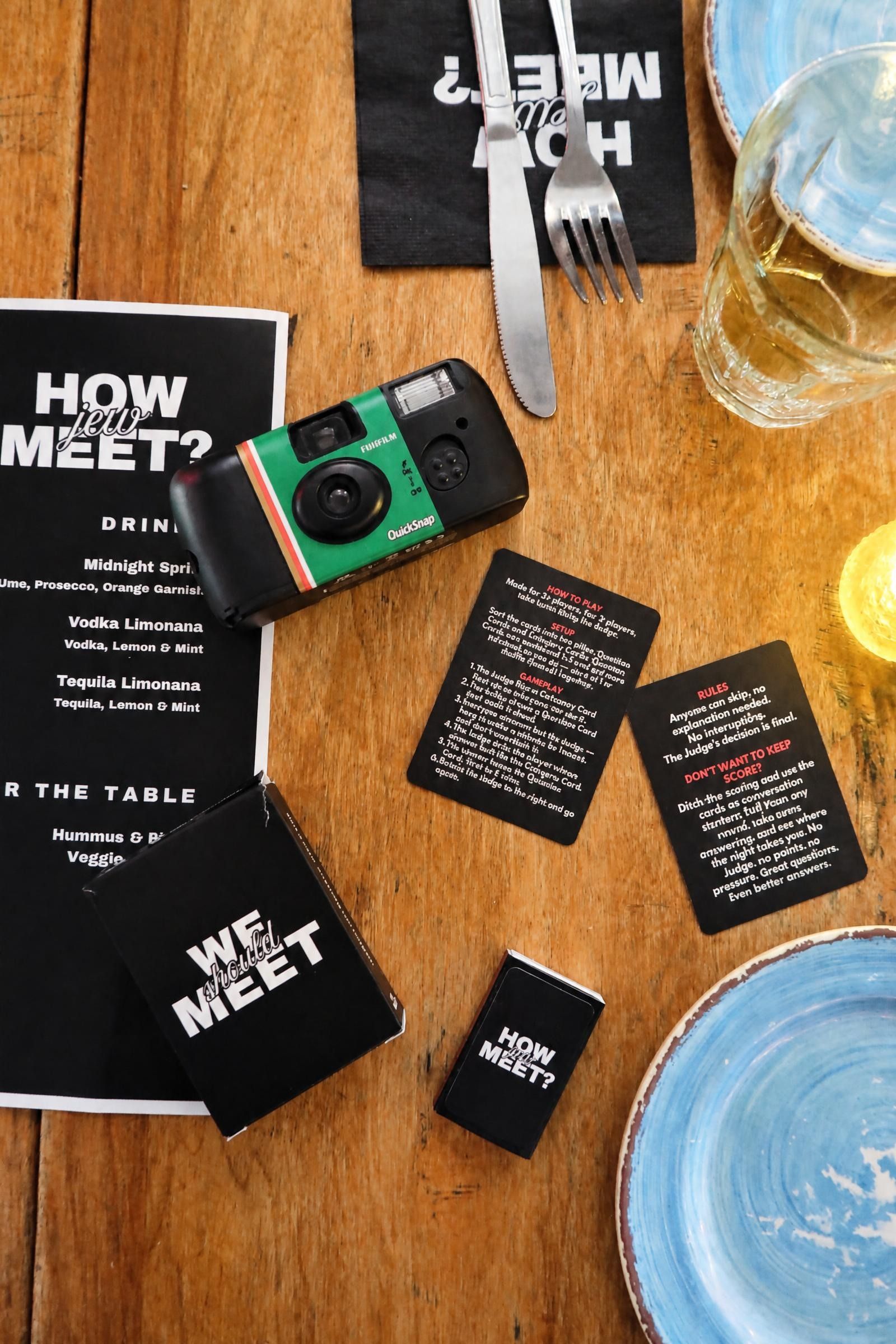 We Should Meet cards, rules, and a disposable camera on a How Jew Meet dinner table