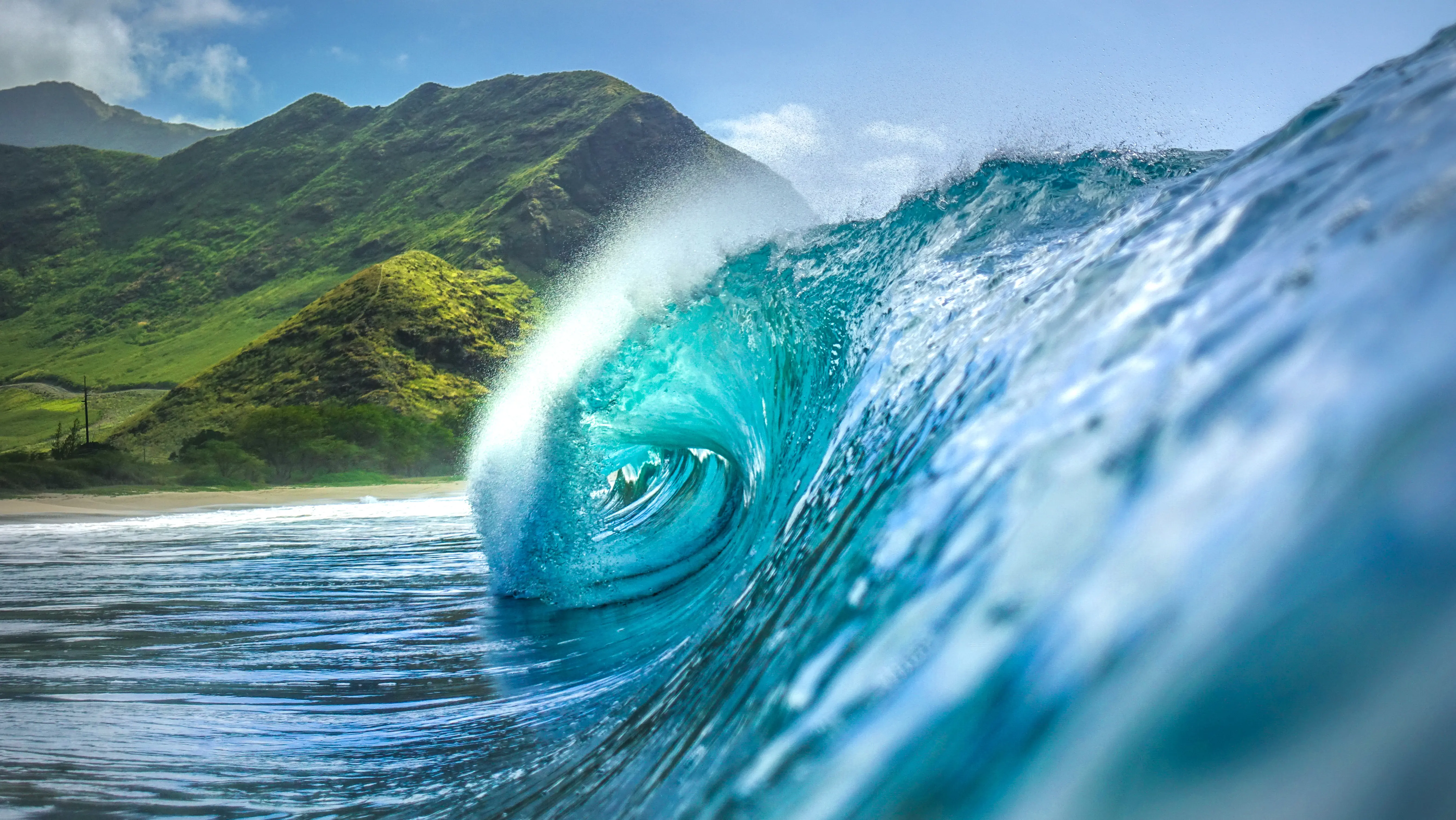 A large blue wave breaking into the ocean.