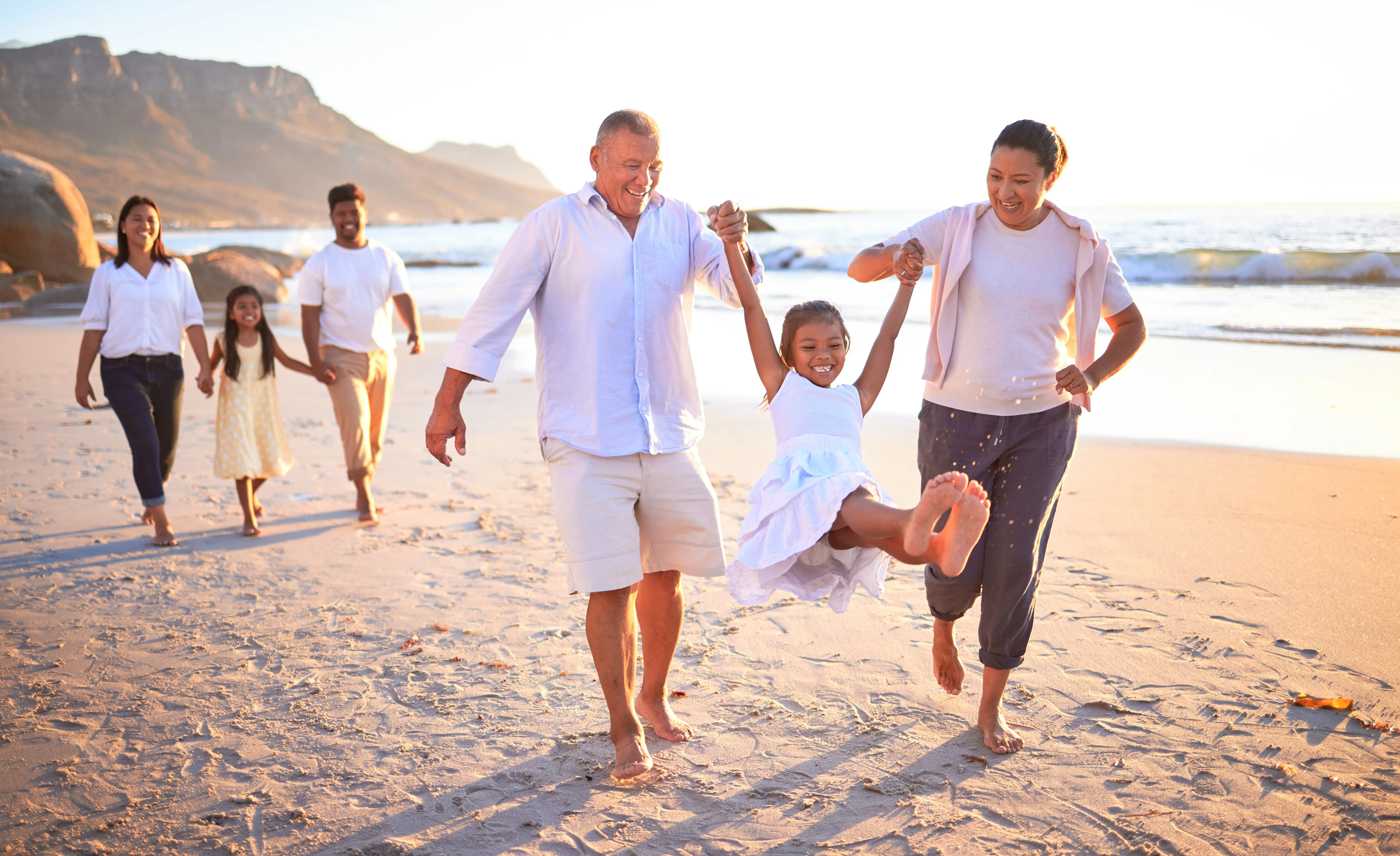 A family walking on the beach holding hands.