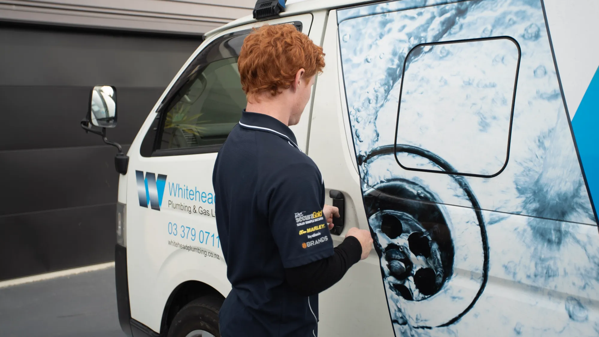 Plumber opening the side door of a branded Whitehead Plumbing & Gas van