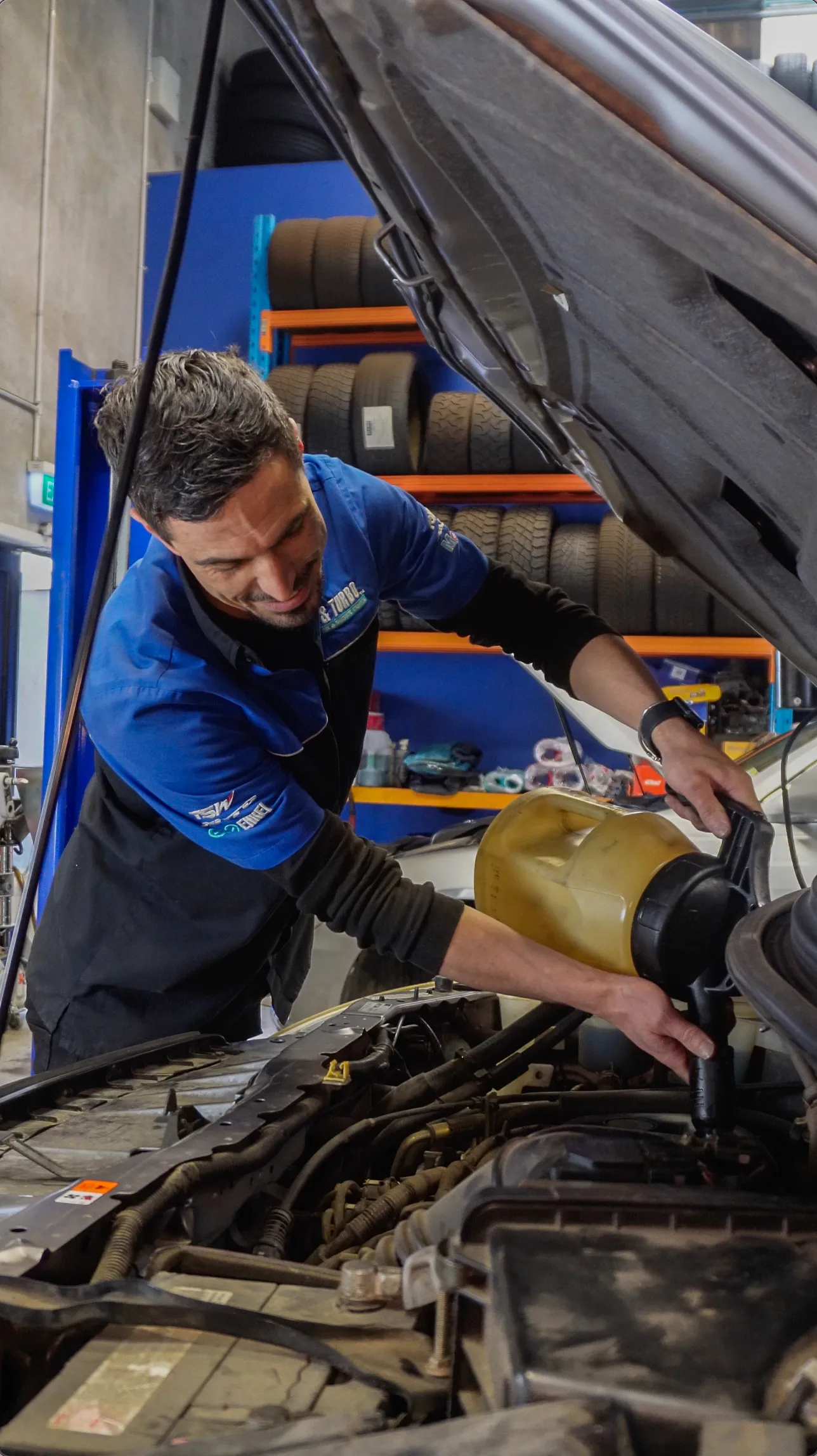 Mag & Turbo technician topping up oil under the bonnet