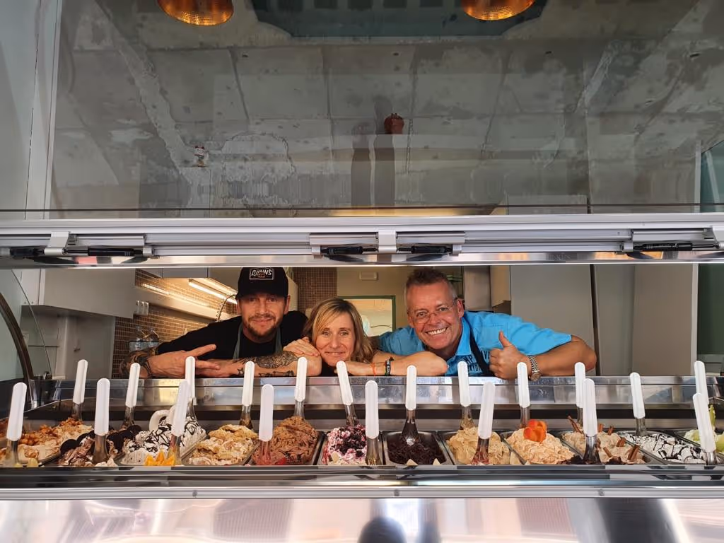 Eisfachschule begleitet erfolgreiche Eröffnung einer Eisdiele in Athen. Eisdiele mit Inhabern hinter der Eistheke mit vielfältigen Sorten von Speiseeis.