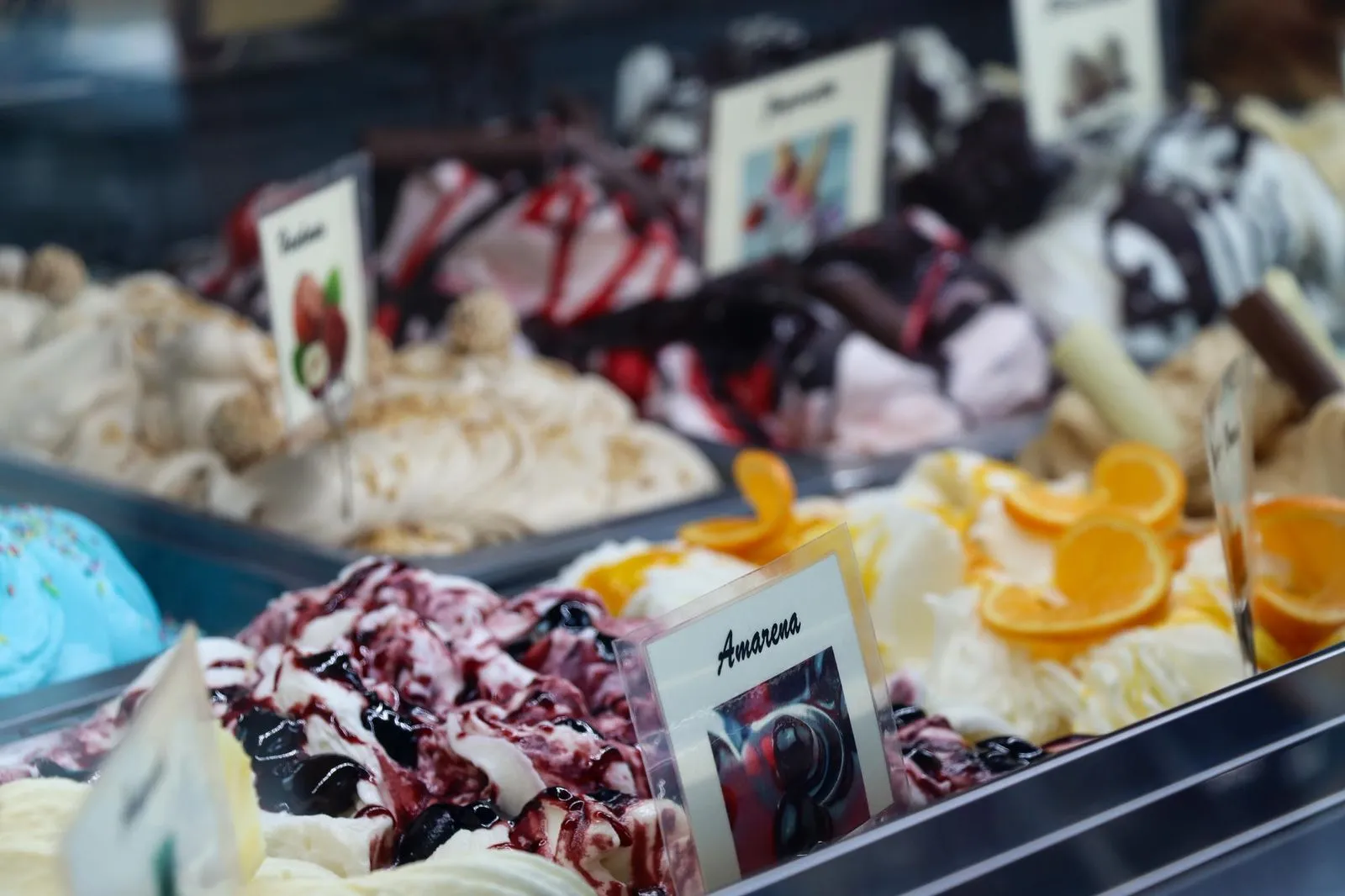 Vielfältige Sorten handwerklich hergestelltes Speiseeis in der Eistheke, darunter Amarena, Schokolade, Kokos und Zitrusvarianten