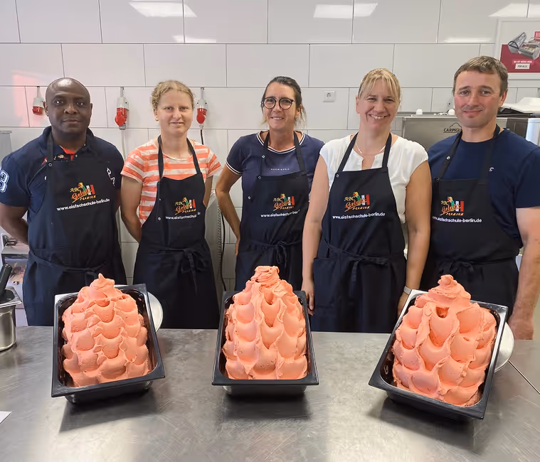Teilnehmergruppe im Speiseeis Seminar der Eisfachschule Berlin präsentiert frisch hergestelltes Erdbeer-Eis in der Lehrküche