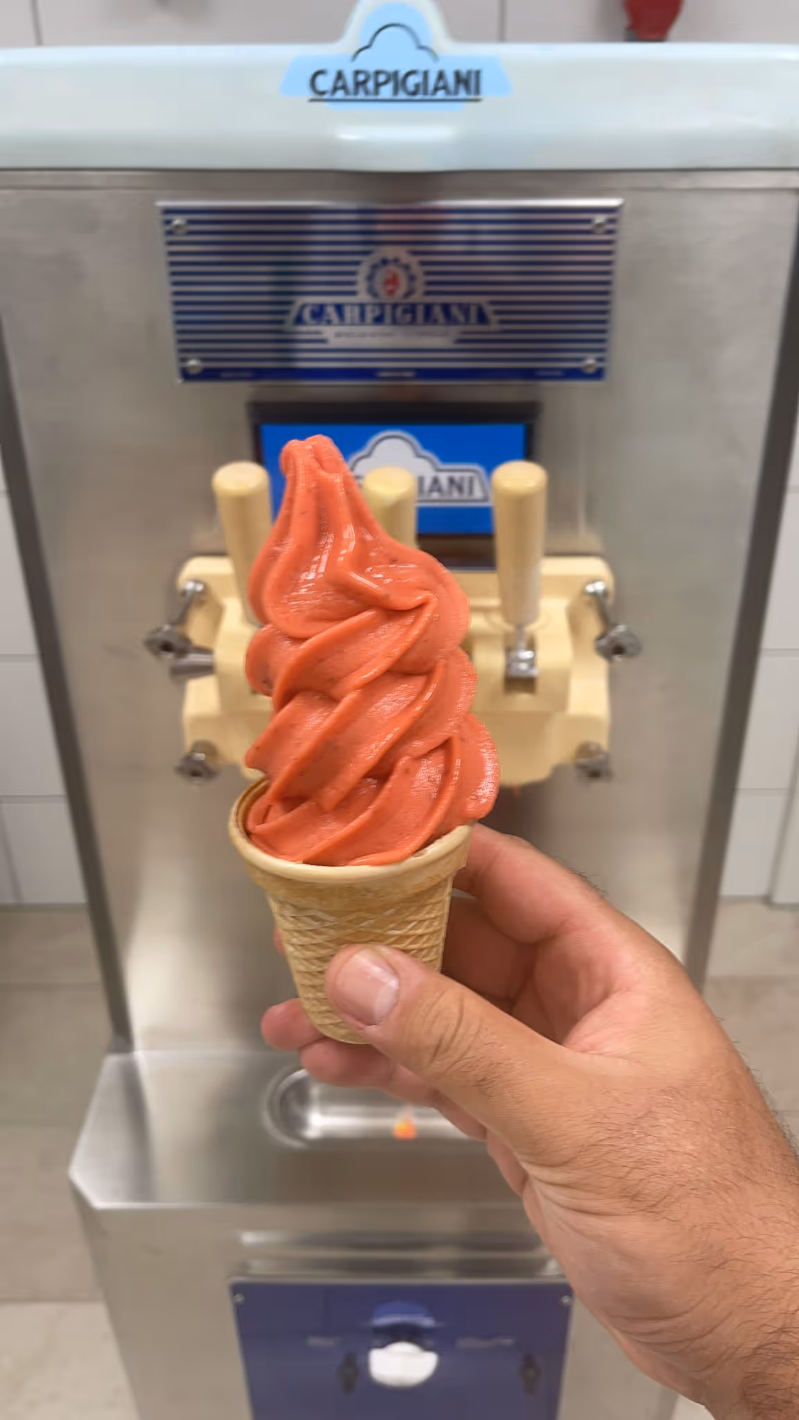 Erdbeer-Softeis in Waffel vor einer Carpigiani Softeismaschine