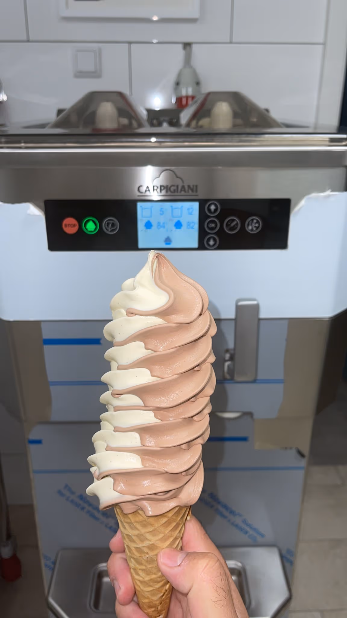 Softeis in Waffel mit Vanille-Schoko-Mix vor einer Carpigiani Softeismaschine