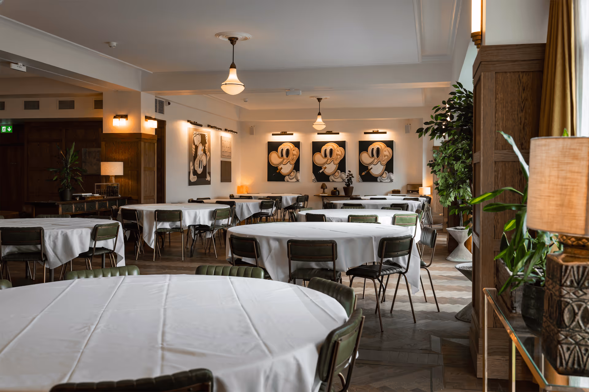 Fantasia event venue dining room with round tables, vintage Mickey Mouse artwork, and Art Deco pendant lighting in Reykjavik