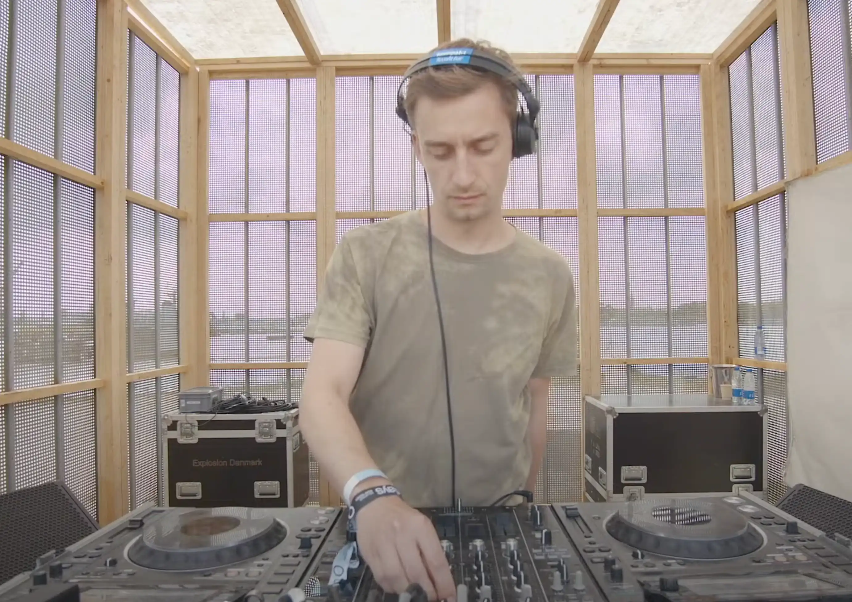 Søren Kinch performing a DJ set at Drift Radio during O Days Festival on August 2, 2024 — standing behind the decks, wearing headphones, focused on the mixer, with colorful stage lights and the crowd visible in the background.