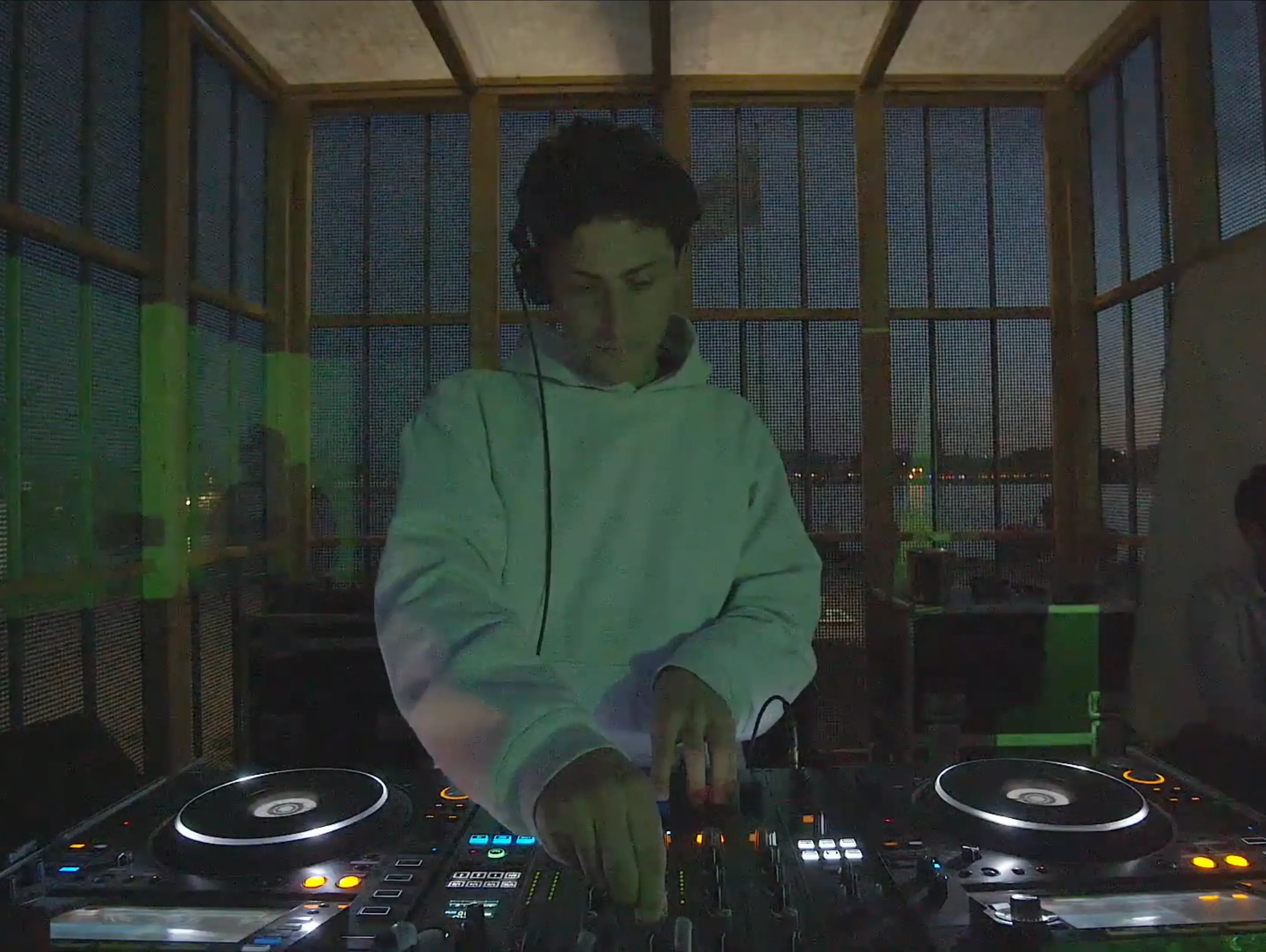 Eliott Litrowski performing a DJ set at Drift Radio during O Days Festival on August 2, 2024 — focused on the mixing console, wearing headphones, with dynamic stage lighting and the audience faintly visible behind him.