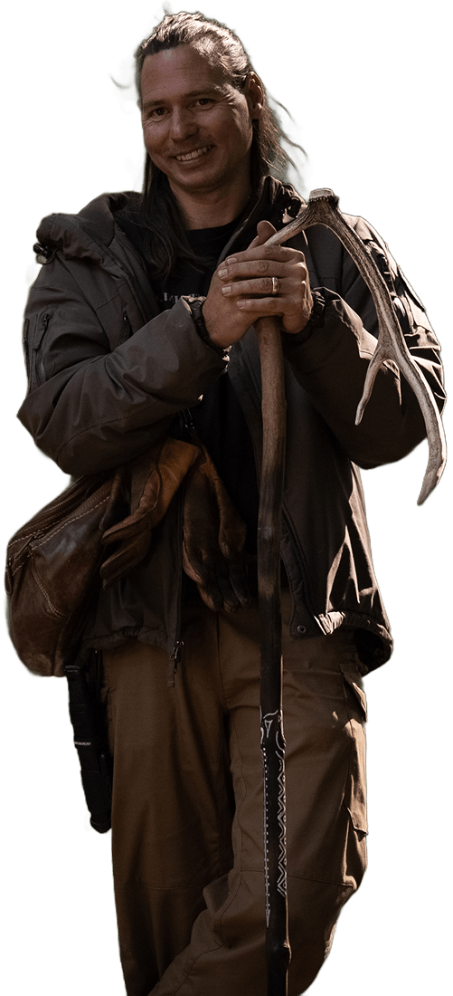 Gion Salutz, lächelnd in Outdoor-Kleidung hält einen Spazierstock mit Geweihgriff.