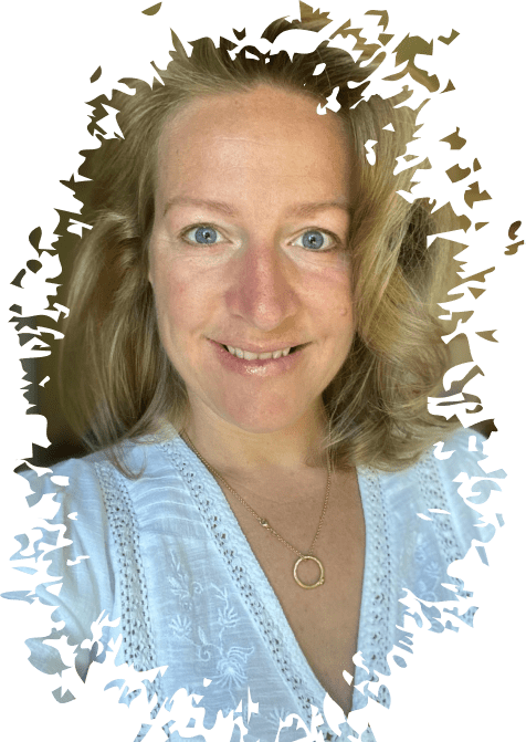 Frau mit blonden, welligen Haaren, trägt ein weißes besticktes Oberteil und eine Goldkette mit rundem Anhänger.