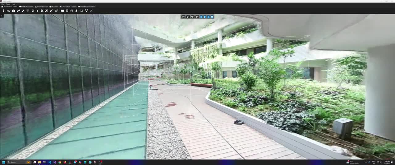 Indoor courtyard with plants, wooden walkway, stone path, and a water feature along a reflective wall under a multi-level building.