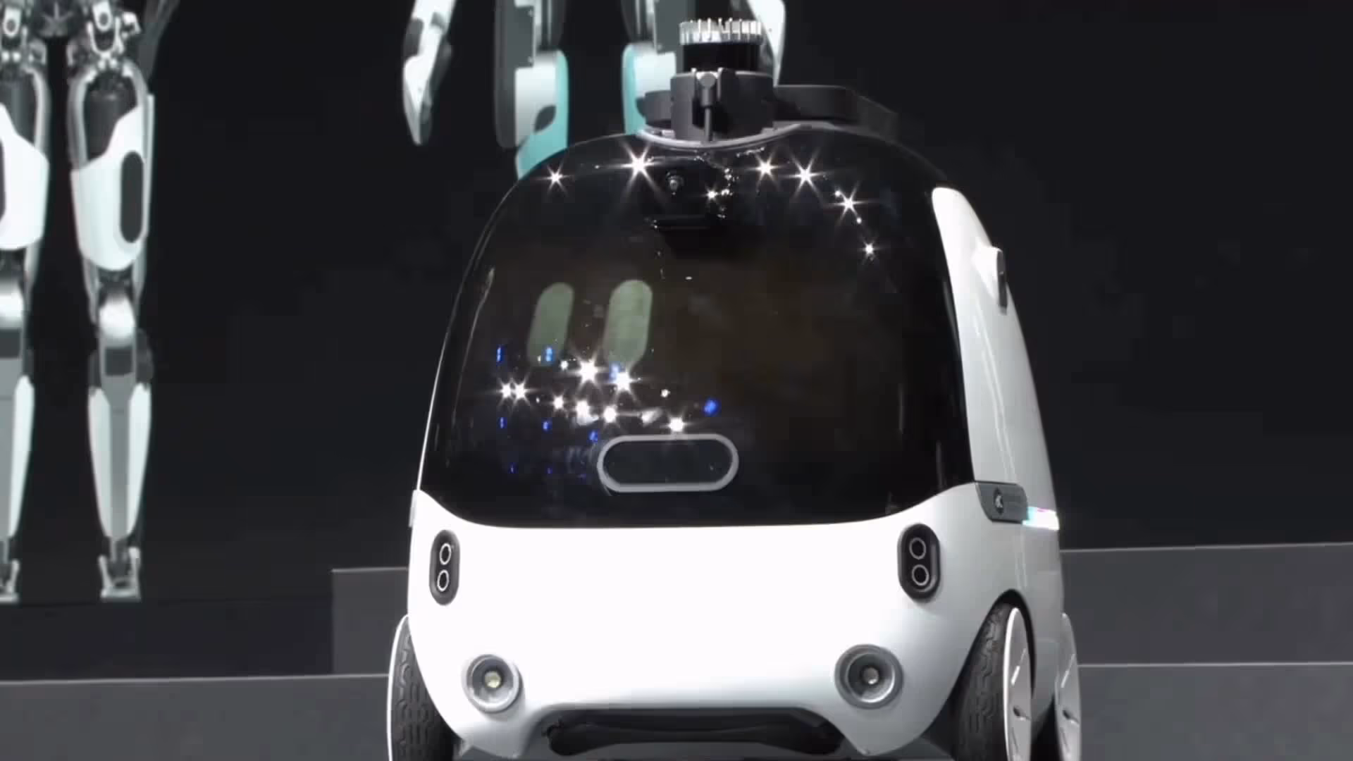 Front view of Dasher: a compact white autonomous vehicle with a large black windshield and sensors on top and front.