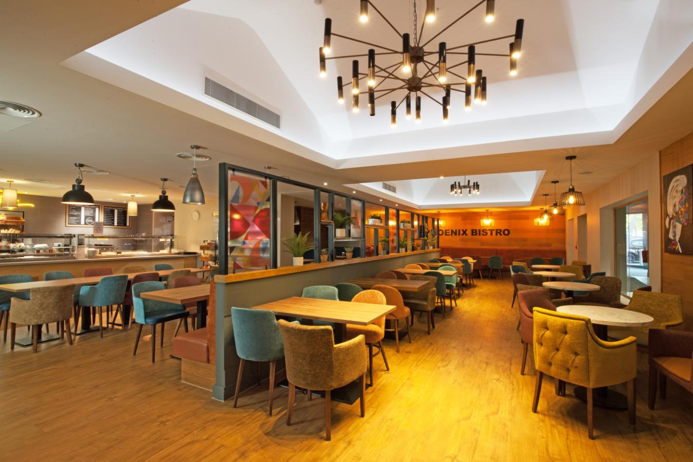 Modern office amenities Essex featuring Phoenix Business Park’s stylish on-site bistro with colourful seating, warm lighting and space for informal meetings and staff breaks.