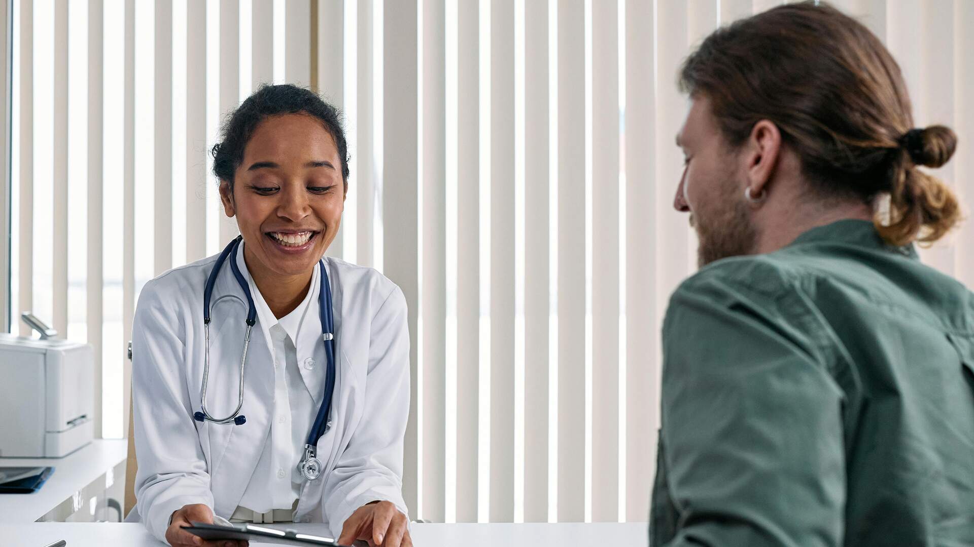Female doctor showing patient medical results on tablet during clinic consultation.