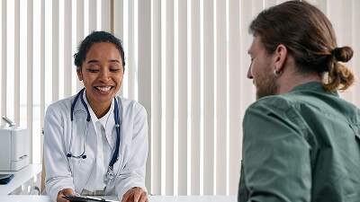Female doctor showing patient medical results on tablet during clinic consultation.