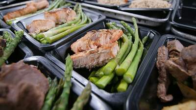Healthy prepared meals with grilled salmon and asparagus in meal prep containers, representing nutritious, medically tailored food options.