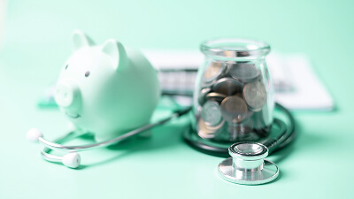 Piggy bank, stethoscope, and a jar filled with coins on a medical document, representing how HSAs and financial tools support patient healthcare spending.”