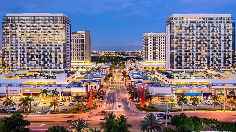 Doral, FL cityscape at dusk with modern buildings and palm-lined boulevard.