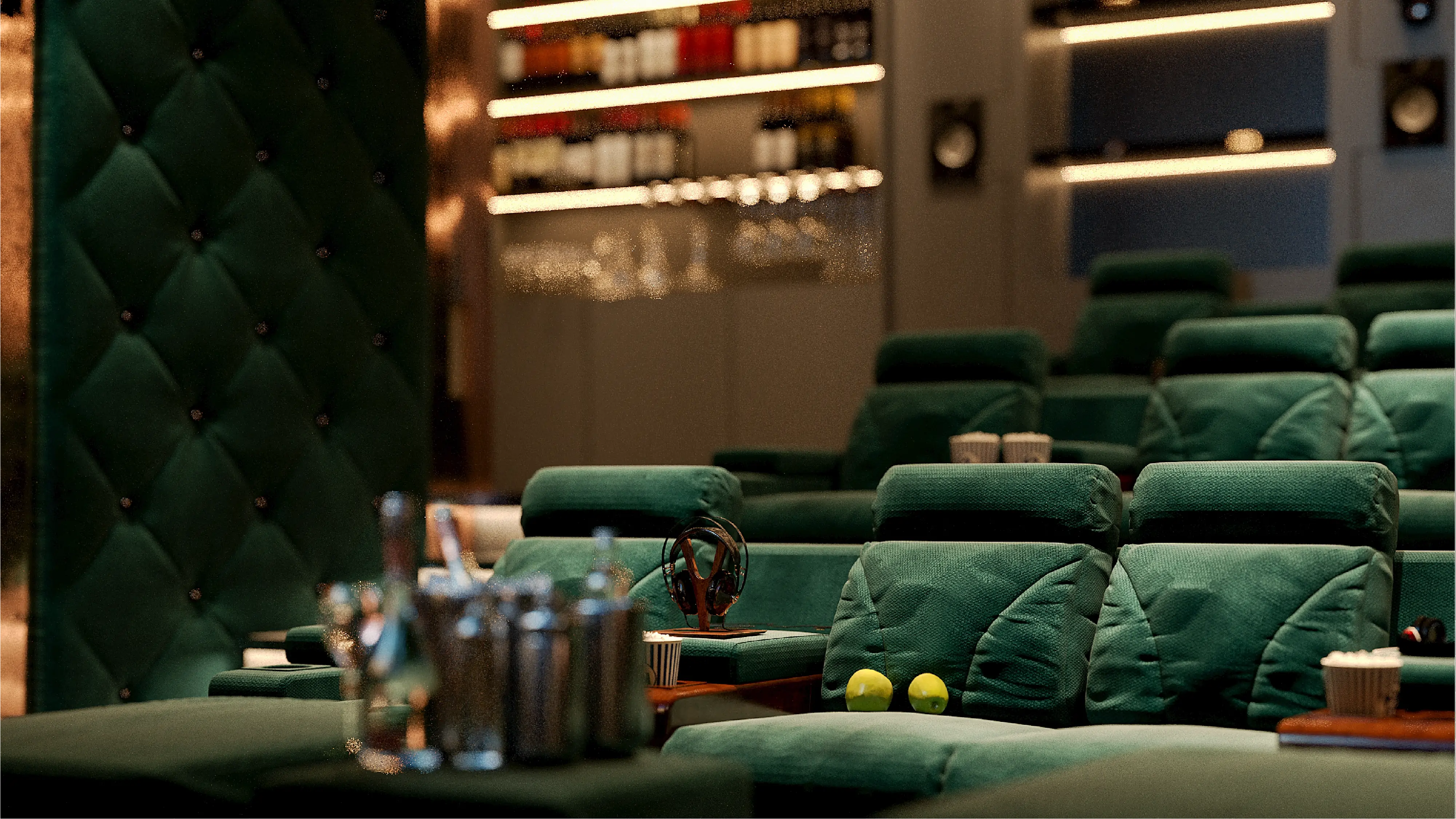 صندلی‌های سبز مخملی راحتی در یک سالن سینمای خانگی با چند سیب سبز روی یکی از صندلی‌ها.