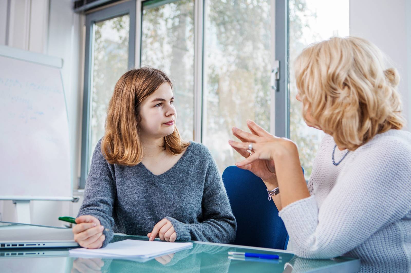 Nachhilfelehrerin erklärt Schülerin den Lernstoff im persönlichen Gespräch im modernen Nachhilfezentrum