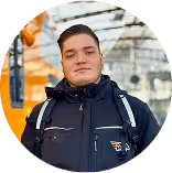 Mann in dunkler Jacke vor orangem, glänzendem Zug in moderner Halle.