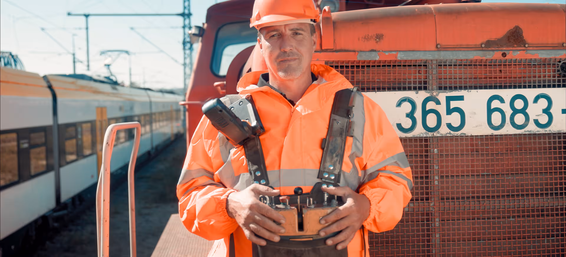 Zug fährt bei Sonnenuntergang über Gleise, im Hintergrund leuchtender Himmel und ruhige Landschaft.