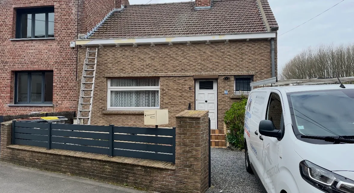 Façade d'une maison en brique avec porte blanche, fenêtre à rideaux, une camionnette blanche garée devant. détection fuite 